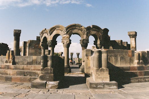 Ancient ruined arches of Zvartnots Cathedral under clear sky in Armenia.