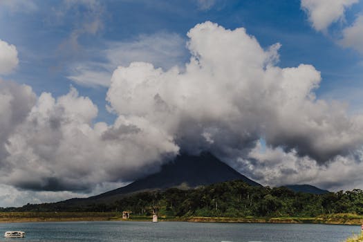 A stunning landscape of Arenal Volcano with clouds and a serene lake view, capturing nature's beauty.