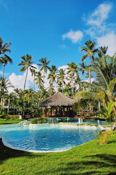 Relax by the turquoise pool amidst lush palms in Punta Cana's tropical resort.