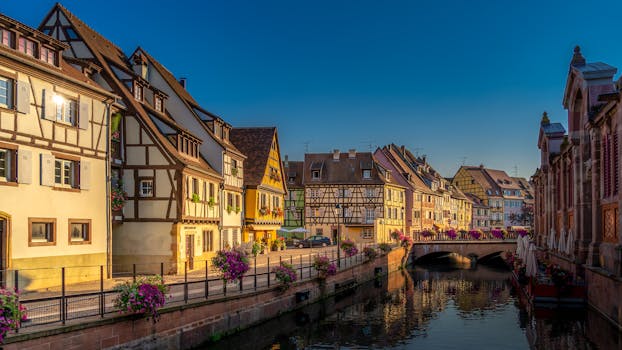Scenic view of Colmar, France featuring picturesque half-timbered houses and a tranquil canal at sunset.