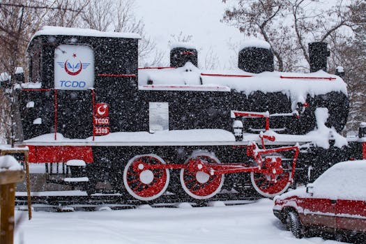 A historic steam engine blanketed in snow during winter in Erzurum, Türkiye, creating a nostalgic scene.