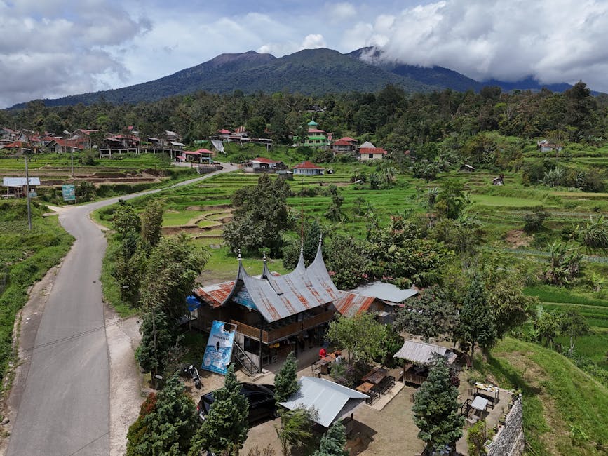 A beautiful aerial shot of a Minangkabau village with lush green rice fields and mountains in West Sumatra, Indonesia.