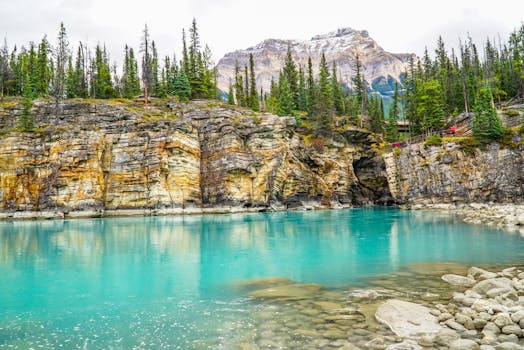 Vibrant turquoise waters of Maligne Canyon in Jasper National Park, surrounded by rocky cliffs and pine trees.
