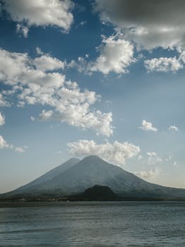 Stunning view of Volcán de Agua in Guatemala with a backdrop of clouds and clear blue sky.