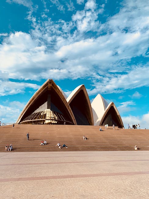 Iconic Sydney Opera House with visitors relaxing on sunny steps under a vibrant blue sky.