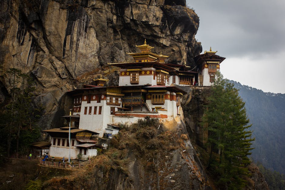 Exterior of Taktsang Lakhang monastery located on stony mountain near green trees under cloudy sky