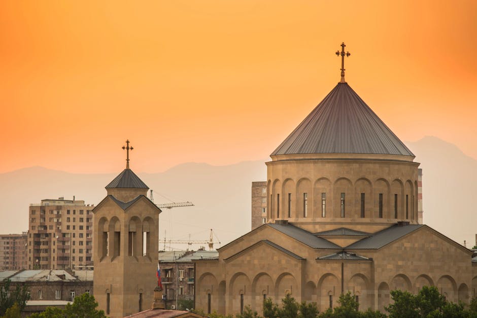 Beautiful image of an Armenian church with intricate architecture against a vibrant orange sunset in Yerevan, Armenia.