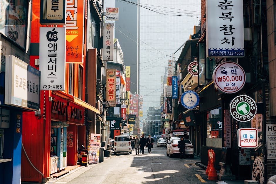 A bustling urban street in Seoul, filled with neon signs, shops, and pedestrians.