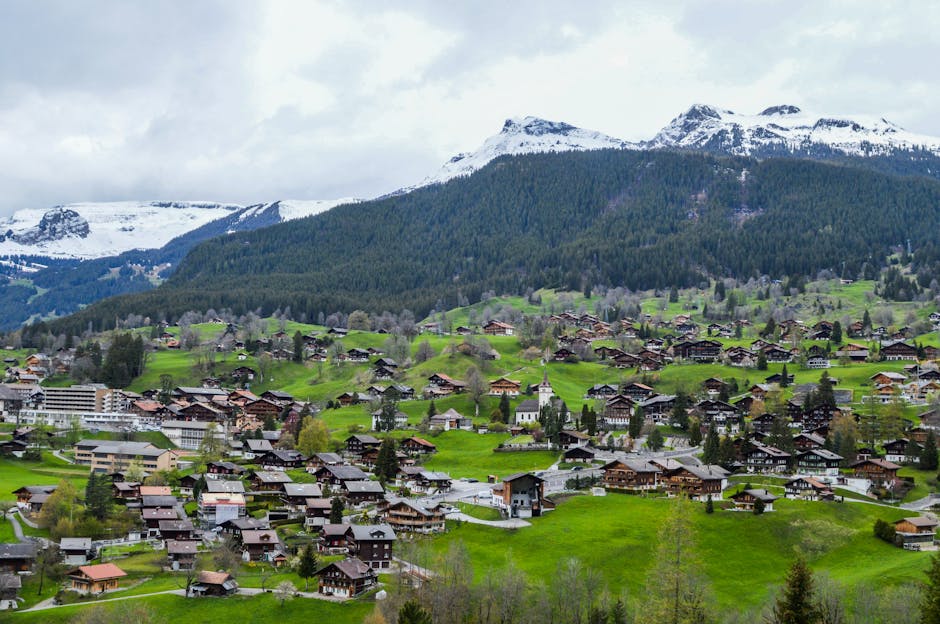 From above view of old dwelling houses on bright hillside near mountain under cloudy sky in countryside