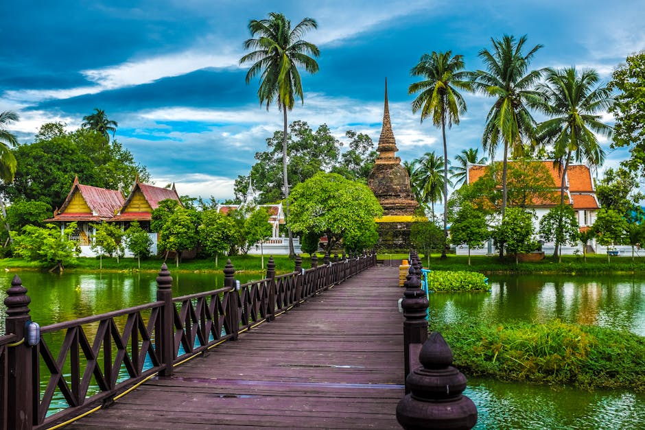 Explore the tranquil beauty of Sukhothai's temple surrounded by lush greenery and serene waters.