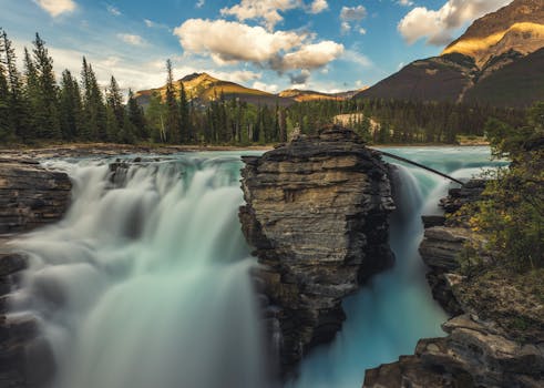 Stunning view of Athabasca Falls surrounded by lush forests and rocky mountains in Jasper National Park.