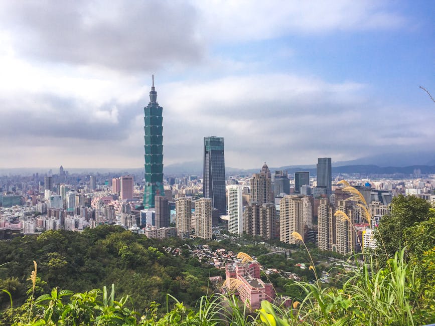 A breathtaking aerial view of Taipei City and Taipei 101 surrounded by urban skyscrapers and lush greenery.