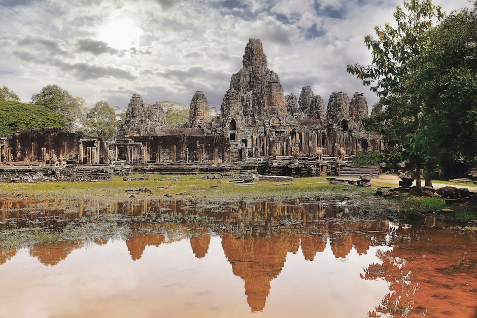 Stunning reflection of Bayon Temple, a historic Khmer landmark in Cambodia, under a dramatic cloudy sky.