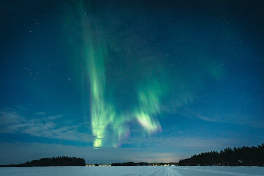 Stunning aurora borealis over snowy field in Vaala, Finland during winter night.