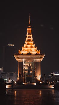 Striking image of an illuminated pagoda in Phnom Penh, Cambodia at night with urban backdrop.