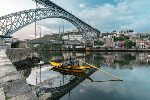 Dom Luís I Bridge over the Douro River with colorful boats and cityscape reflection in Porto, Portugal.