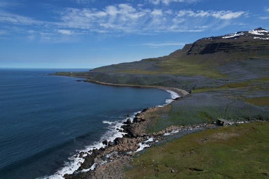 Aerial view of the picturesque coastline near Seydisfjordur, Iceland, showcasing mountains and ocean under a clear sky.