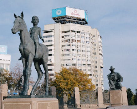 Monumental statues and Soviet-era architecture in Almaty, Kazakhstan, under clear skies.