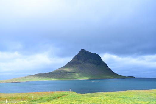 Majestic view of Kirkjufell mountain by the sea under a cloudy sky in Iceland.