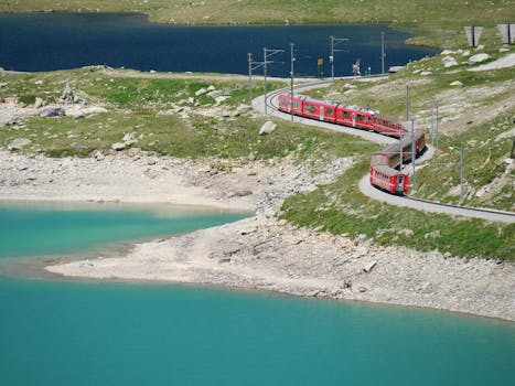 Red train curving through the beautiful Swiss Alps landscape near Bernina Pass.