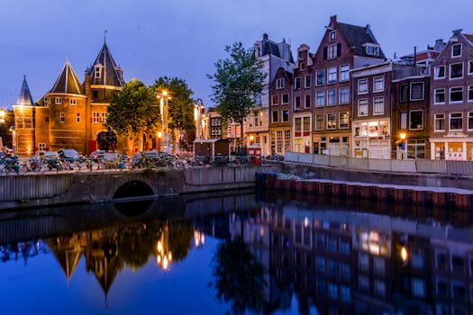 Charming Amsterdam canal and historic houses illuminated at night. Captivating reflections on the serene water.
