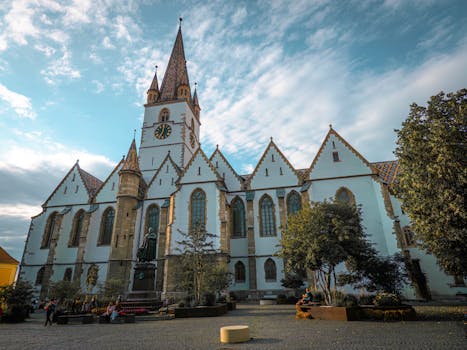 Explore the majestic Gothic architecture of Sibiu's historic church under a vibrant summer sky.