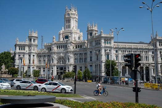 View of the iconic Palacio de Cibeles, Madrid with busy traffic and clear sky.