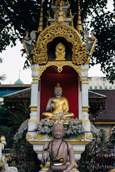 Golden Buddha statue at Wat Chiang Man in Chiang Mai, Thailand, surrounded by intricate gold decorations.