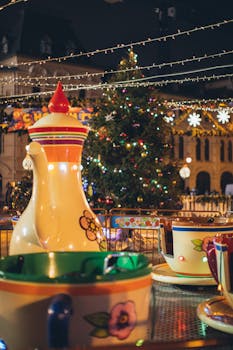 Merry go round with large colorful traditional Russian teapot and cups in city park decorated in New Year style in evening