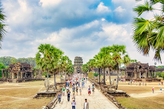 Tourists explore the iconic Angkor Wat in Siem Reap, Cambodia, under a bright sky.