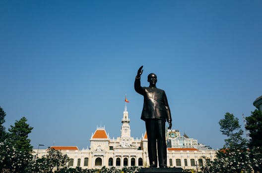 Iconic Ho Chi Minh statue with City Hall in backdrop on a clear day in Vietnam.