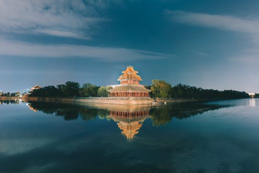 Tranquil night scene of the Northwest Tower at Beijing's Forbidden City reflecting on the water.