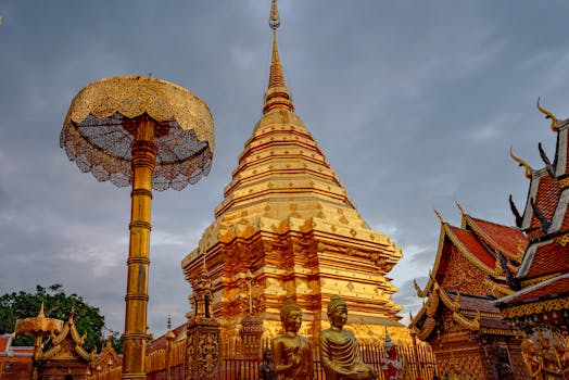 Stunning view of the golden Wat Phra That Doi Suthep pagoda under cloudy skies in Chiang Mai, Thailand.