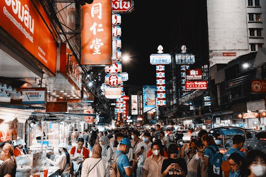 Vibrant night life on a busy street in Bangkok's Chinatown filled with lights and crowds.