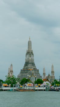 Stunning view of Wat Arun by the Chao Phraya River in Bangkok during the day.