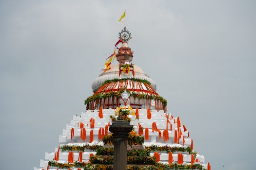 A beautifully decorated Indian temple dome with vibrant flowers and flags under a clear sky.